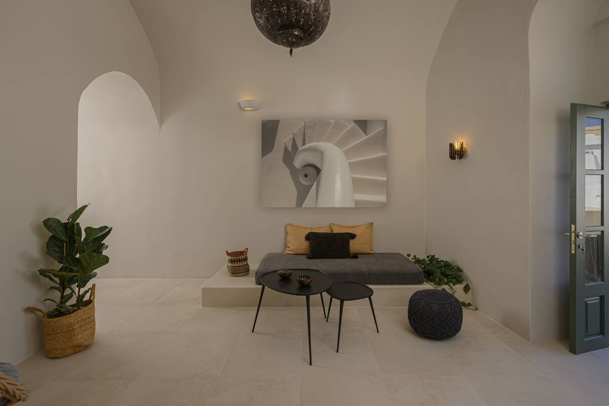 Un interior moderno con un sofá, dos mesas negras, un cuadro abstracto grande y una cesta decorativa.