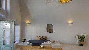 A minimalist bedroom with a bed, bedside table, and a large window. - Elements Cave Suites (Santorini)
