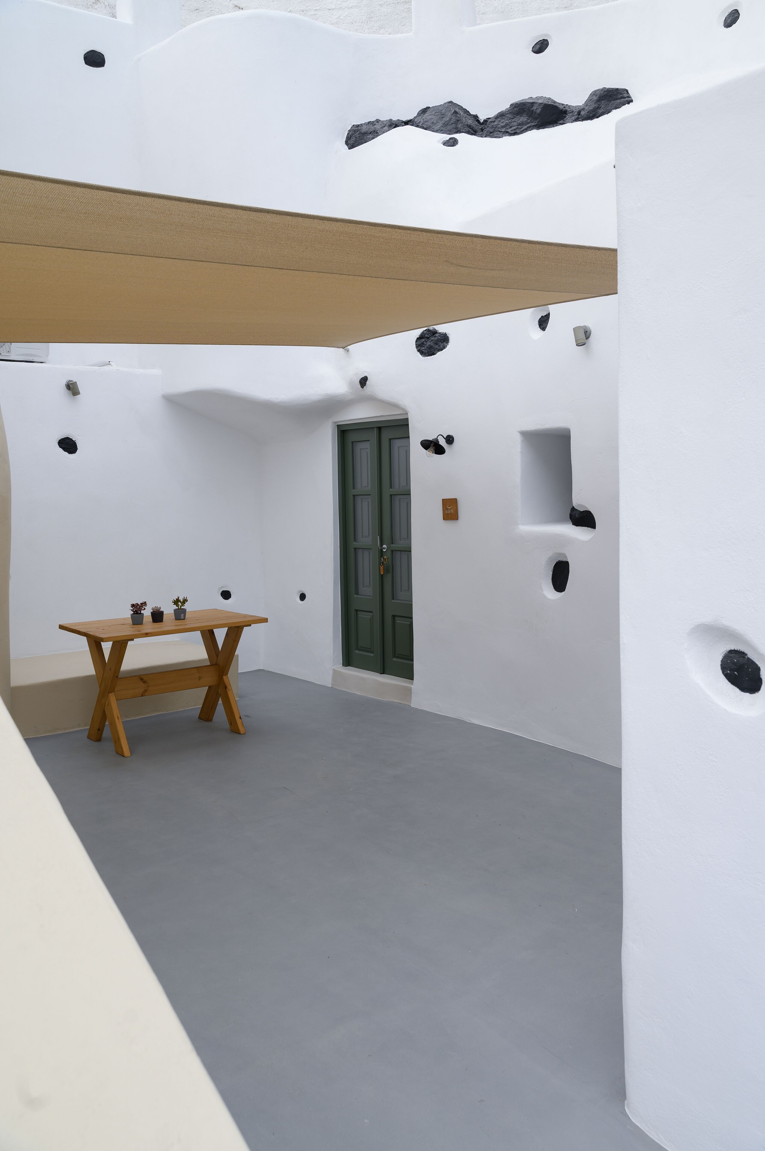 A minimalist interior with a wooden table, a green door, and white walls with black accents.