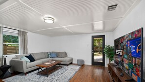 A modern living room with a sectional sofa, a coffee table, a rug, and a flat-screen TV displaying ESPN. - Spacious Patio + Close to The Square + Pet Friendly + Full Kitchen (San Marcos)