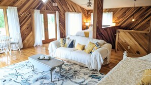 A cozy room with a wooden ceiling, a sofa with patterned cushions, a small table, and a large window with curtains. - A Romantic Getaway on the Bourbon Trail (Willisburg)