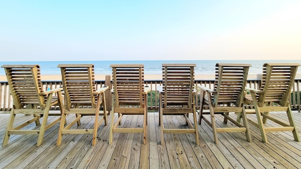 A wooden deck with four wooden chairs facing a beach. - Beachfront Retreat l Hot Tub l Gulf Views, Wraparound Deck, Sleeps 12, Pet-Friendly, & More (Gilchrist)