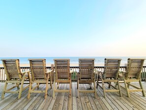En træterrasse med fire træstole ud mod stranden.