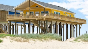 A yellow building with a wooden deck and a balcony. - Beachfront Retreat l Hot Tub l Gulf Views, Wraparound Deck, Sleeps 12, Pet-Friendly, & More (Gilchrist)