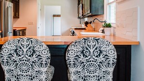 Une cuisine avec deux chaises à motifs, un plan de travail en bois et des luminaires suspendus.