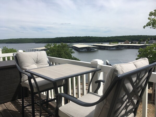 A deck with a table and chairs overlooking a marina with boats and a lake.