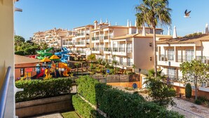 A residential area with multi-story buildings, a playground, and a palm tree.
