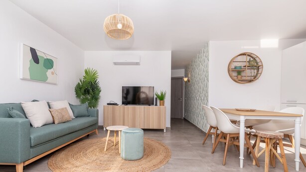 A modern living room with a sofa, TV, and dining area.