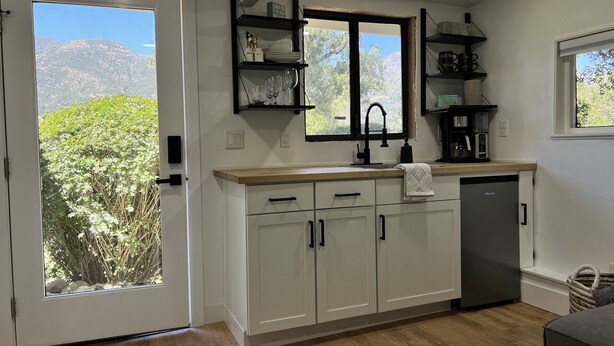 A kitchen with white cabinets, a wooden countertop, a dishwasher, and a window with a view of greenery and mountains. - Mountain Views/Studio in Montecito. 7-10 min to beach or downtown SB (Montecito)