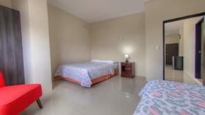Una camera d'albergo con un letto, una sedia, un comodino e uno specchio.