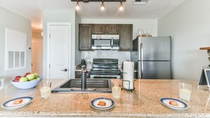 A modern kitchen with granite countertops, stainless steel appliances, and wooden cabinets. - New Labor Day Reduction! Sunny Beach Days at Sunrise Breeze (Galveston)