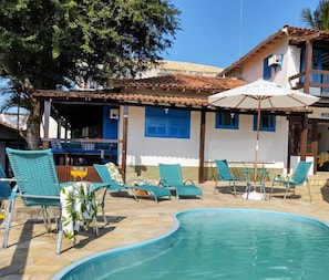 Una piscina al aire libre, sombrillas, sillones reclinables de piscina