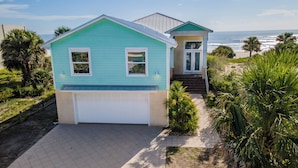 Ein zweistöckiges Haus mit Garage, einer Veranda und Blick aufs Meer.