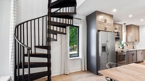 A modern kitchen with a spiral staircase, wooden flooring, and built-in appliances. - Breezy Chic: Fresh Spring Vibes at The Modern Oak walkable to town! (Three Oaks)