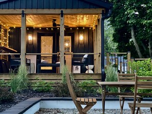 Une cabane en bois dotée d’une véranda, d’un espace salon extérieur et d’un jardin.