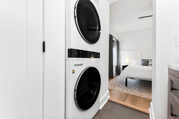 Une chambre d’hôtel moderne équipée d’un lave-linge à deux bacs, d’un lit et d’une table de chevet.
