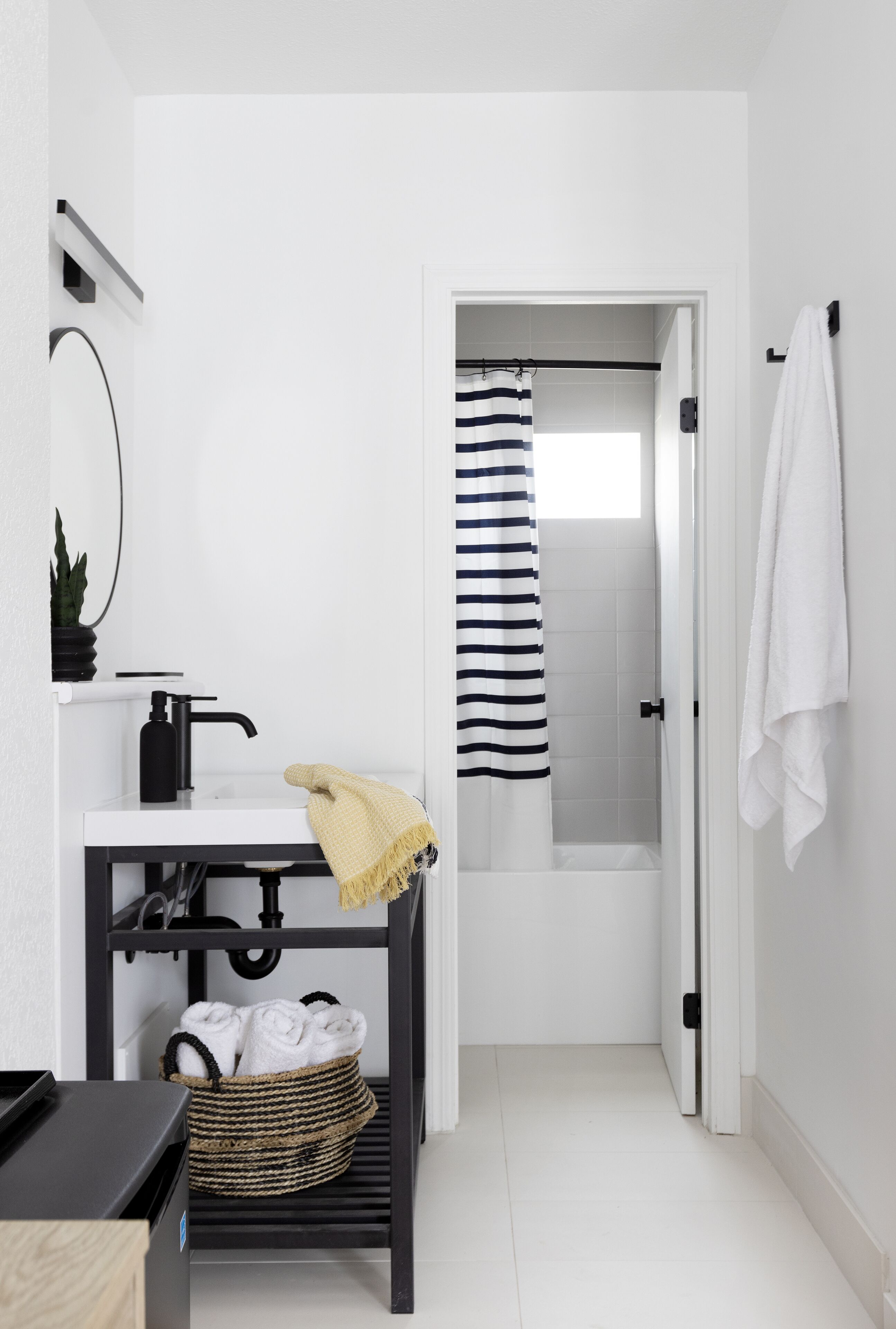 A modern bathroom with a white sink, black faucet, and a towel rack.