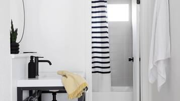 A modern bathroom with a white sink, black faucet, and a towel rack.
