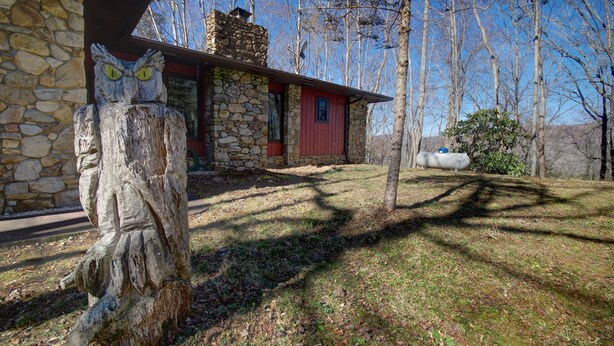Une maison en pierre avec une porte rouge et une cheminée en pierre.