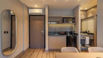 Une chambre d’hôtel compacte équipée d’une kitchenette, d’un four à micro-ondes, d’une machine à café et d’un petit réfrigérateur.