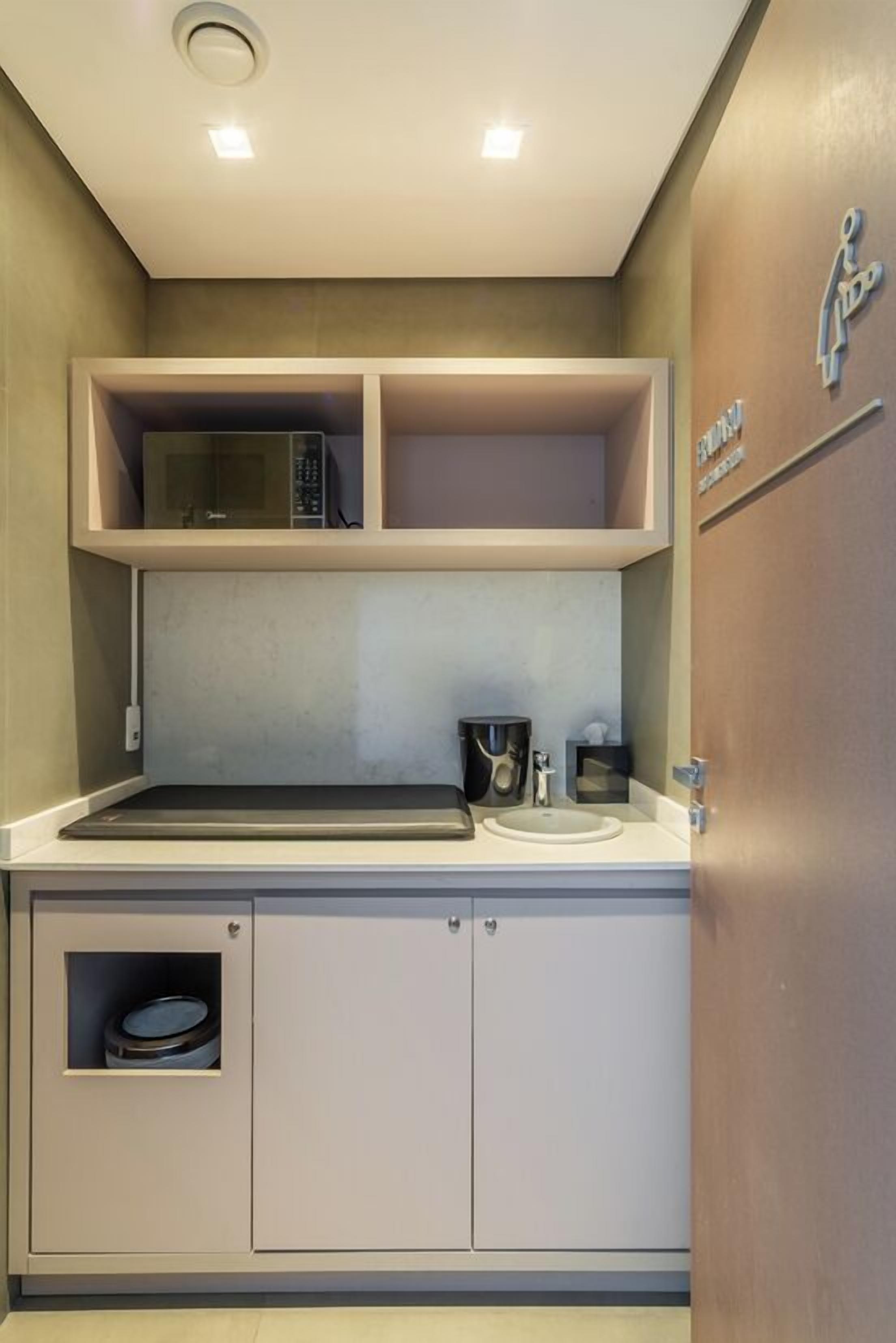 Una kitchenette compacta con microondas, pileta y alacenas.