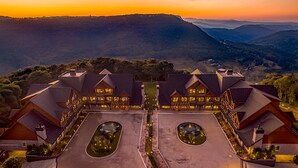 A hotel with a symmetrical layout, featuring a central courtyard with a circular water feature, surrounded by multiple buildings with large windows and a mountain backdrop. - Château Laghetto Collection (Gramado)