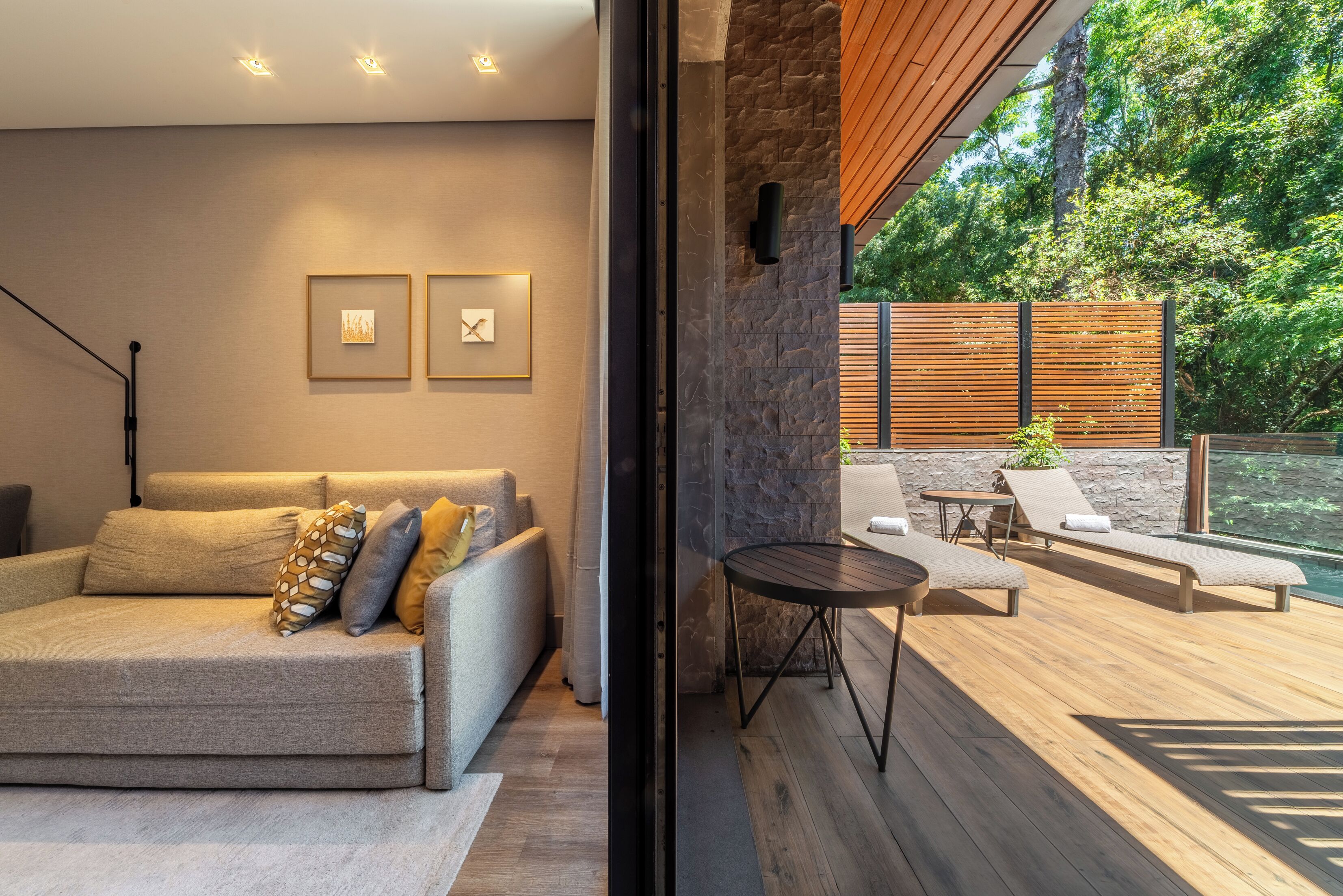 Una sala de estar moderna con sofá, una mesa de centro y vistas a una terraza exterior con sillones y una mesa.