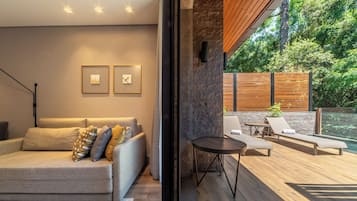 Una sala de estar moderna con sofá, una mesa de centro y vistas a una terraza exterior con sillones y una mesa.