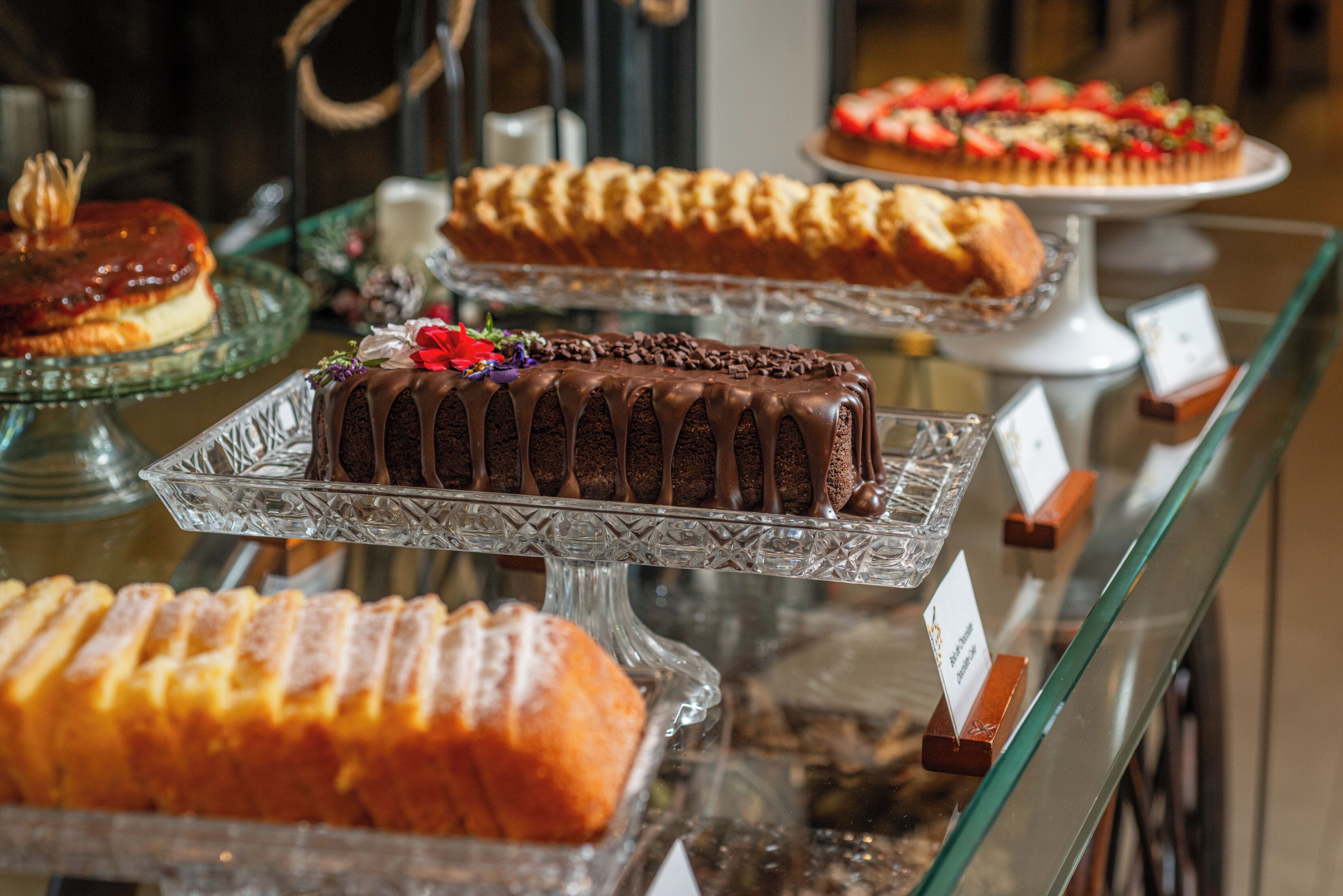 A display of various cakes on glass stands.