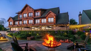 A large wooden building with multiple windows and a fire pit in the foreground. - Château Laghetto Collection (Gramado)