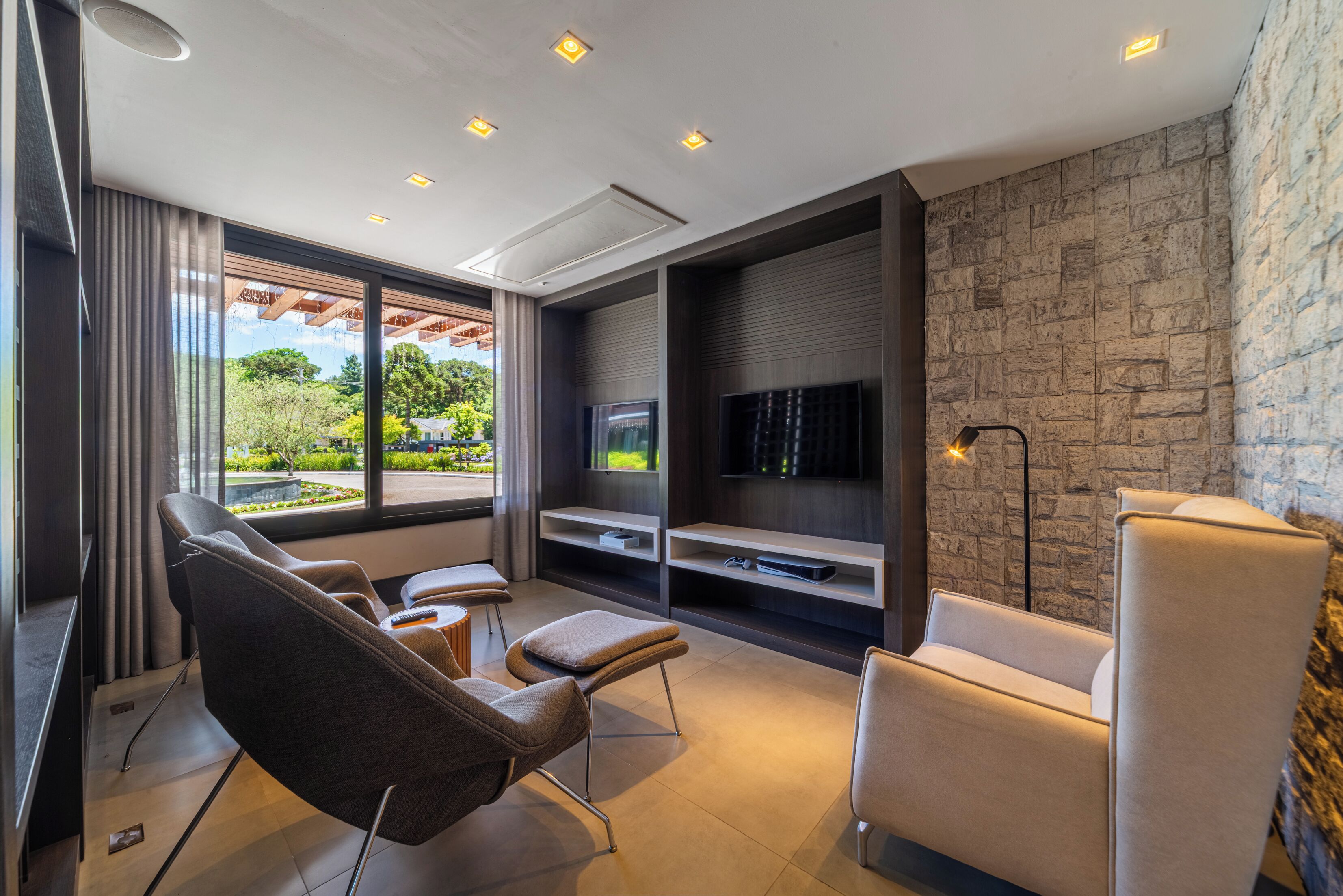 Un salon moderne doté d’un téléviseur à écran plat, de sièges confortables et d’un mur en pierre.