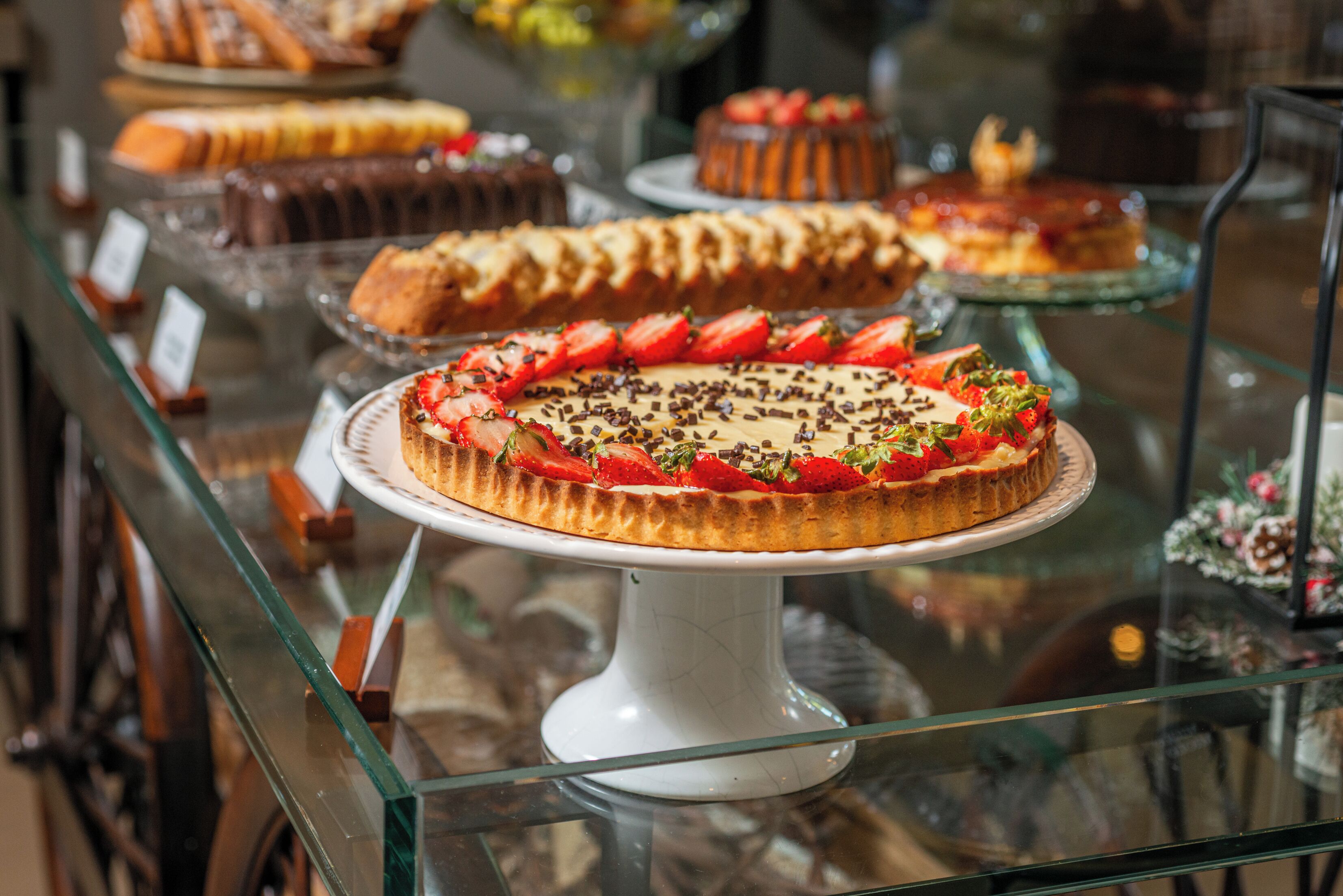 A variety of desserts displayed on glass shelves in a bakery.