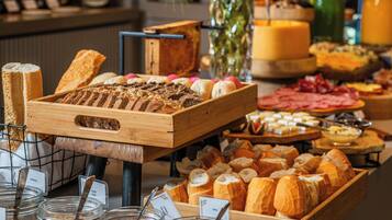 A buffet with various breads, cheeses, and meats.