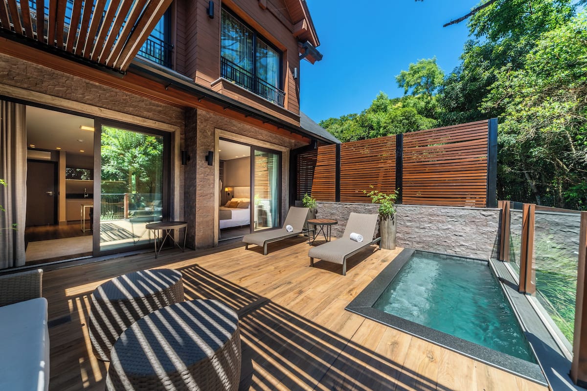 Une maison moderne dotée d’une piscine, de grandes fenêtres et d’un espace patio.