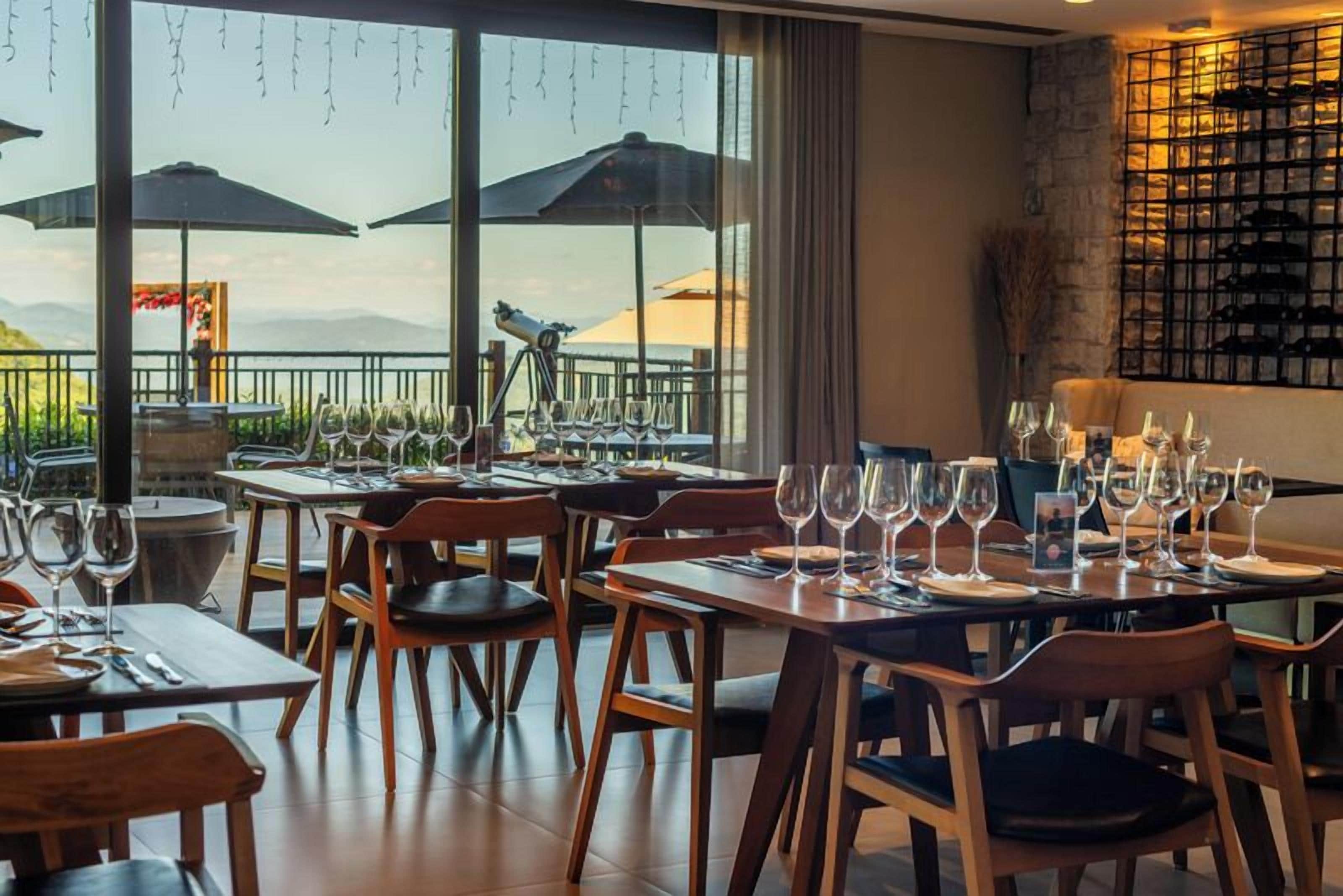 Un restaurante con mesas dispuestas para comer, sombrillas exteriores y vistas a las montañas.