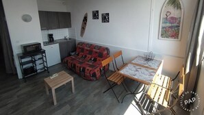 A compact living space with a kitchenette, a dining area with a table and chairs, a sofa, and a small bench.