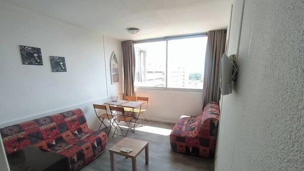 A living room with a sofa, a coffee table, and a dining area with chairs and a table.