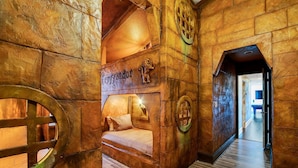 A cozy room with a stone wall, a bed, and a circular window.