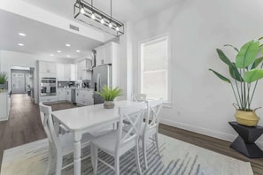 A modern kitchen with white cabinetry, a dining area with a white table and chairs, and a large potted plant. - *Pearl of Springfield*-WIFI, AC, PATIO (Jacksonville)