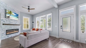 Un salon avec une cheminée, un canapé et un ventilateur de plafond.