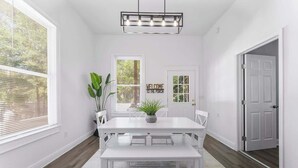 Une salle à manger avec une table blanche, un banc et une plante en pot.