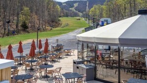An outdoor patio with tables and chairs, overlooking a scenic landscape with trees and a distant hill. - 4th of July Week 2024 Massanutten Resort, 2BDRM 2BA Sleeps 6 (Massanutten)