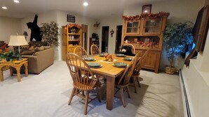 Un coin repas avec une table et des chaises en bois, entouré d’un salon comprenant un canapé et une lampe.