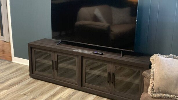 A dark wood TV stand with a flat-screen TV and a remote control. - Sweet Dreams in Sacramento (Sacramento)