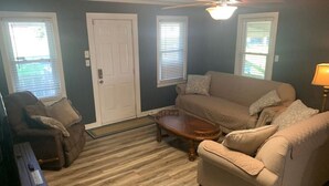 A living room with a beige sofa, a wooden coffee table, and a brown armchair. There is a white door and windows with blinds. - Sweet Dreams in Sacramento (Sacramento)