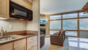 Eine moderne Küche mit Granit-Arbeitsplatten, Holzschränken und einer eingebauten Mikrowelle. Es gibt eine gemütliche Sitzecke mit Kamin und einem großen Fenster mit Blick auf eine verschneite Landschaft.