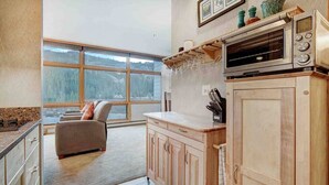 Eine Küche mit Holzausstattung, einer Arbeitsplatte, einem eingebauten Backofen und einem Fenster mit Blick auf eine verschneite Landschaft.