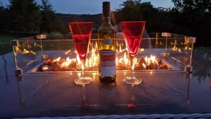 Une bouteille de vin Torrontes, deux verres à vin rouge et un verre de vin rouge sur une table, avec un foyer en arrière-plan.
