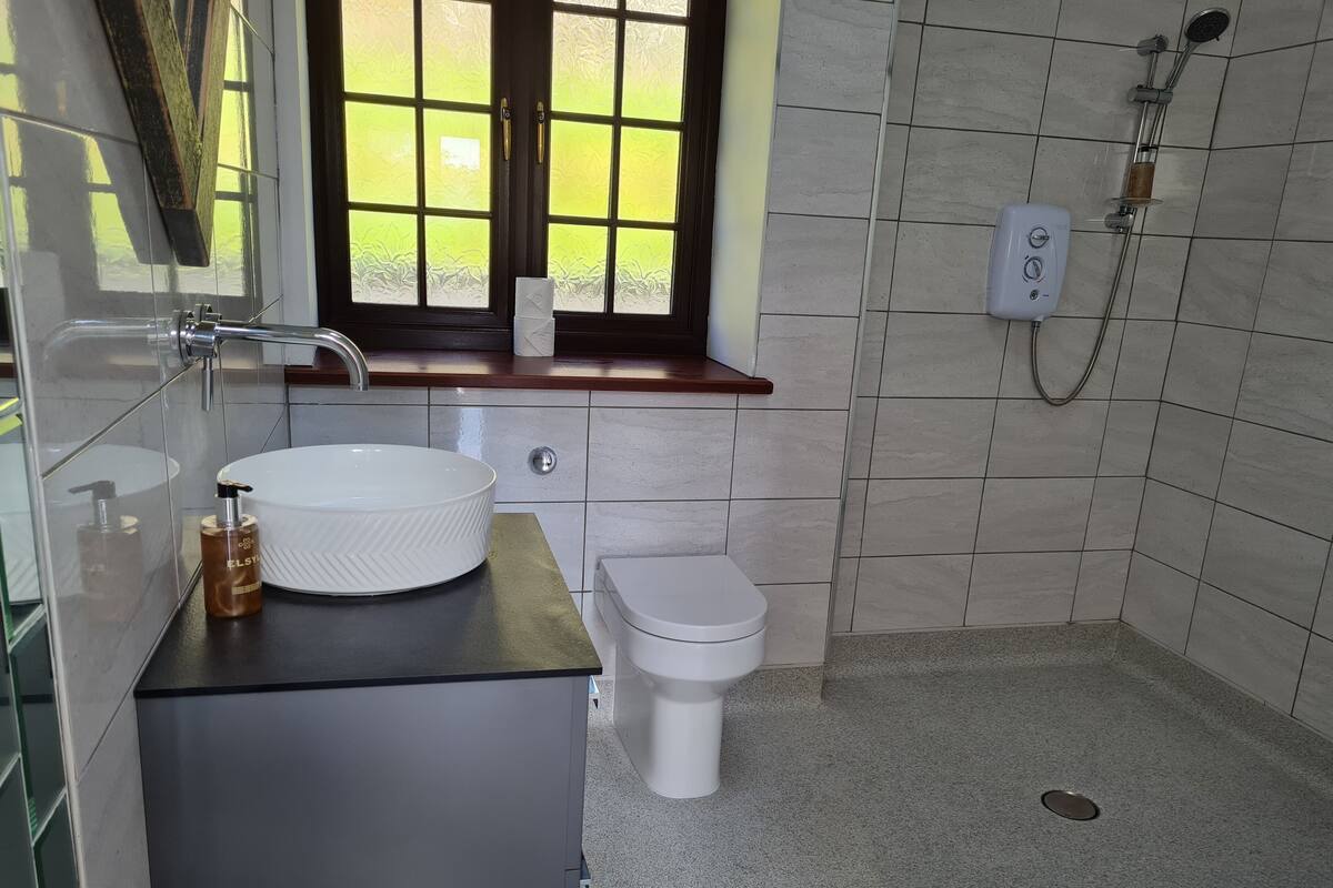 A bathroom with a white sink, toilet, and shower.