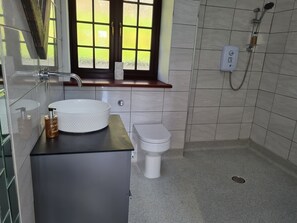 Une salle de bain avec un lavabo, des toilettes et une douche, le tout de couleur blanche.